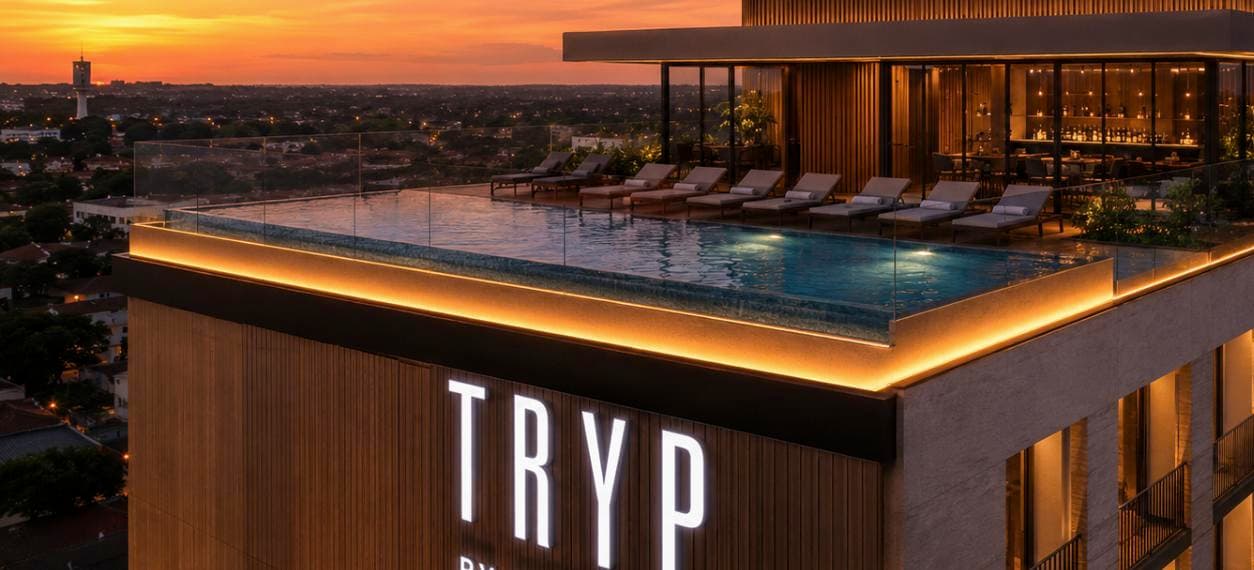 Piscina de borda infinita em rooftop de hotel de luxo ao entardecer, com vista para cidade moderna e arquitetura contemporânea